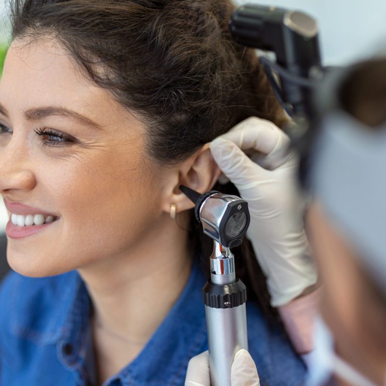 Close up of a female doctor carefully holding the ear of his patient to establish a clearer view of the inside of his ear, to see if he requires hearing aids at a modern clinic